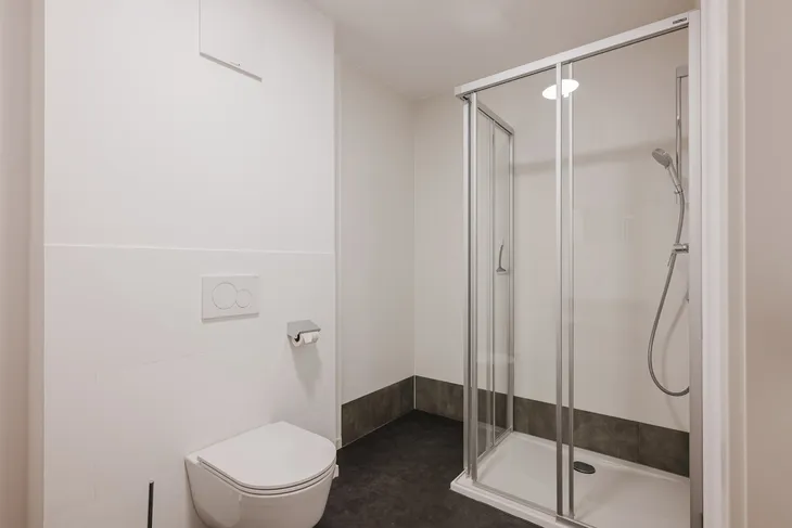 Helles Badezimmer mit Toilette und Duschkabine.