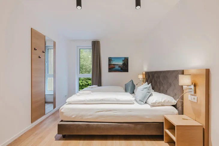 Helles Hotelzimmer mit Doppelbett und moderner Einrichtung.