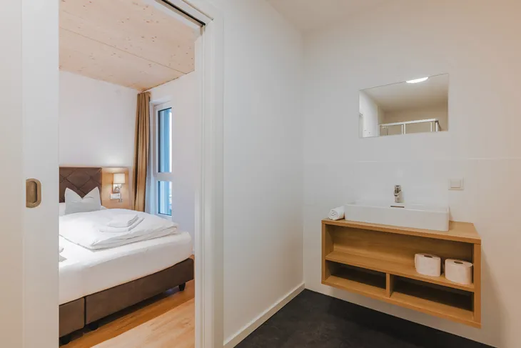 Blick auf ein Hotelzimmer mit Bett und Waschbereich im SeeStrandResort am Klopeiner See.