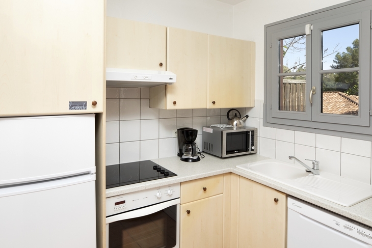 Kleine Küche mit Kühlschrank, Herd, Mikrowelle und Fenster.