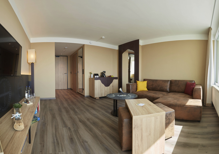 Wohnzimmer einer modernen Familiensuite mit Sofa, Tisch und Holzboden.