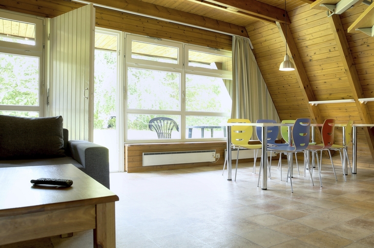 Wohnraum in Nurdachhaus mit Holzwänden und bunter Bestuhlung an der Ostsee