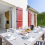 Terrasse eines Ferienhauses mit gedecktem Tisch und roten Fensterläden.