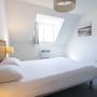 Helles Schlafzimmer mit Doppelbett, Wandlampe und Fenster.