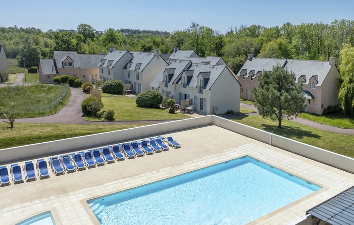 Ferienresort mit Pool, umgeben von grüner Landschaft und mehreren Gebäuden.