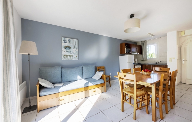 Helles Wohnzimmer mit Sofa, Esstisch und Küchenbereich in der Ferienwohnung.