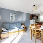 Helles Wohnzimmer mit Sofa, Esstisch und Küchenbereich in der Ferienwohnung.
