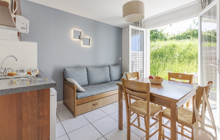 Wohnzimmer mit Sofa, Esstisch und Stühlen, Blick aufs Grüne durch Terrassentür.