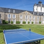 Steinresidenz mit Turm, großer Rasen und Tischtennisplatte im Vordergrund.