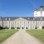 Zufahrtsweg zu einem historischen Schloss mit großem Turm und angrenzender Grünanlage.