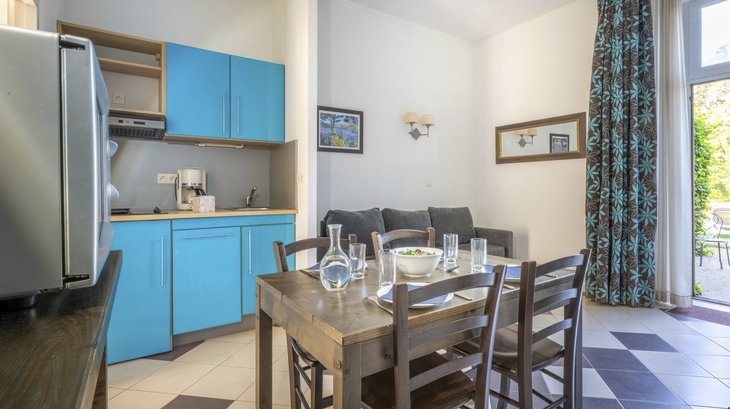 Küchenbereich mit Esstisch, blauen Schränken und Sofa.
