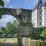 Historisches Schloss mit Torbogen und Gartenansicht.