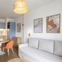 Wohnzimmer mit Sofa, Tisch, Essbereich und Wanddekorationen in moderner Ferienwohnung.