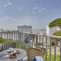 Balkon mit Tisch, Stühlen und Ausblick auf Gebäude und das Meer im Hintergrund.