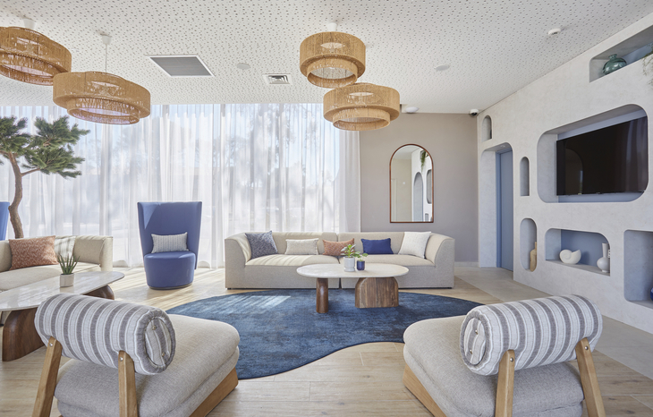Moderne Wohnzimmerlounge mit hellen Möbeln und großen Fenstern.