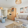 Helles Wohnzimmer mit Sofa, Esstisch und Küchenzeile in einer Ferienwohnung.