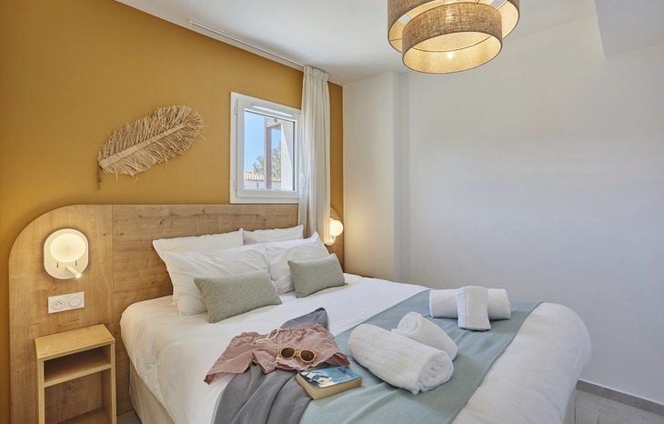 Modernes Schlafzimmer mit Doppelbett, Fenster und dekorativen Lampen.