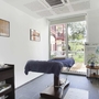 Ein heller Wellnessraum mit Massageliege und großen Fenstern.
