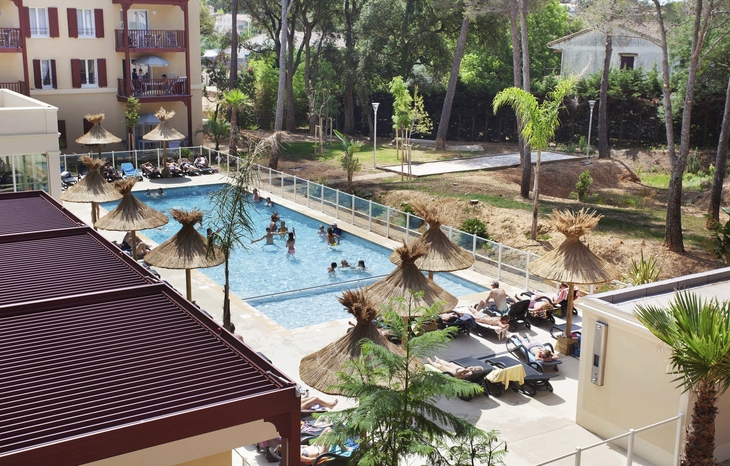 Poolbereich mit Sonnenschirmen und Menschen bei Odalys Résidence Prestige Les Canissons.