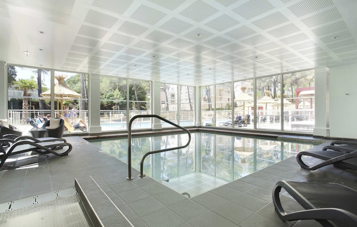 Innenpool mit Liegestühlen und großen Fenstern in einer modernen Residenz.