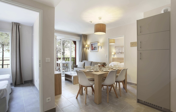 Helles Wohnzimmer mit Esstisch und sechs Stühlen, angrenzend ein Balkon.