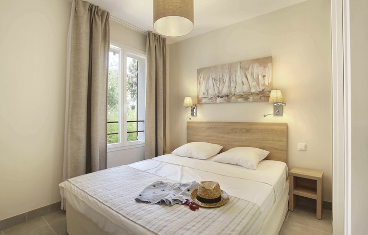 Helles Schlafzimmer mit Doppelbett, dekorativen Kissen und Wandbild über dem Bett.