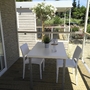 Terrasse mit Tisch, zwei Stühlen und Pflanzen, Blick auf Mobilheim und Garten.