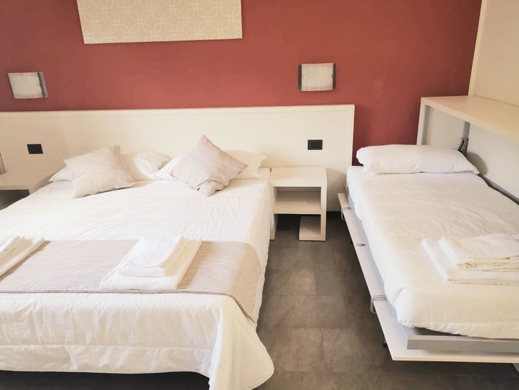 Doppelbett und ausklappbares Bett in modernem Schlafzimmer mit roter Wand