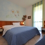 Hotelzimmer mit zwei Lampen, blauen Bettdecken und Blumenbild an der Wand.
