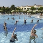 Menschen im Pool bei Wasserübungen in einer Ferienanlage.