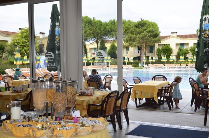 Frühstücksbereich mit Blick auf den Pool in einer Ferienanlage.