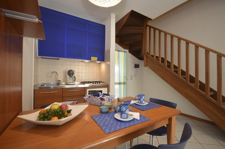 Essbereich mit Holztisch, Treppe und Küchenzeile in Ferienwohnung.