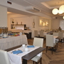 Innenansicht des Frühstücksraums im Hotel mit gedeckten Tischen und Buffet.