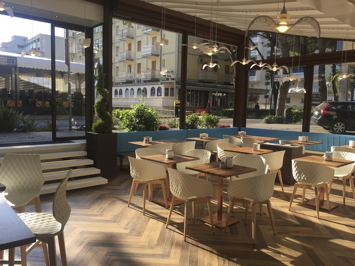 Moderner Speiseraum im Hotel mit Holzboden und großen Fenstern.