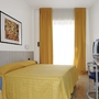 Modernes Hotelzimmer mit gelbem Bett und Vorhängen, Schreibtisch und Fernseher.