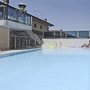 Hotelpool mit Liegestühlen und Sonnenschirmen, im Hintergrund ein Gebäude.