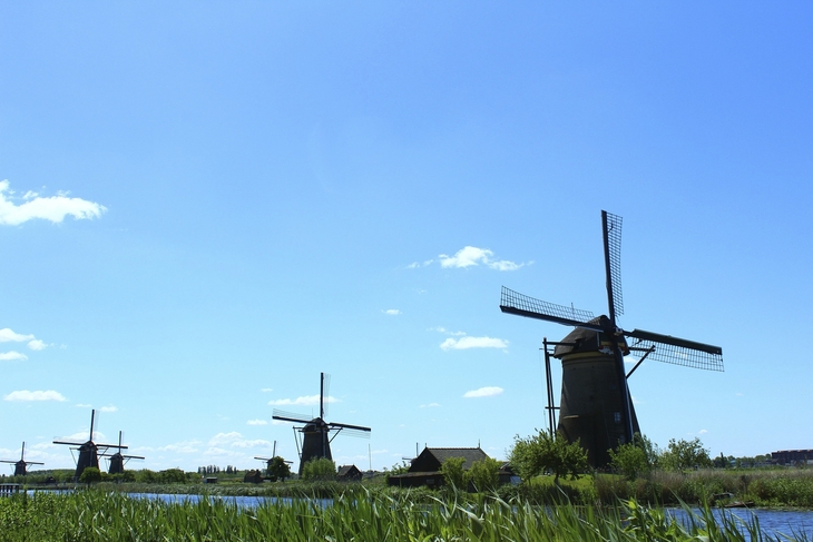Windmühlen in Kinderdijk an einem sonnigen Tag mit blauem Himmel und Wolken.