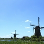 Windmühlen in Kinderdijk an einem sonnigen Tag mit blauem Himmel und Wolken.