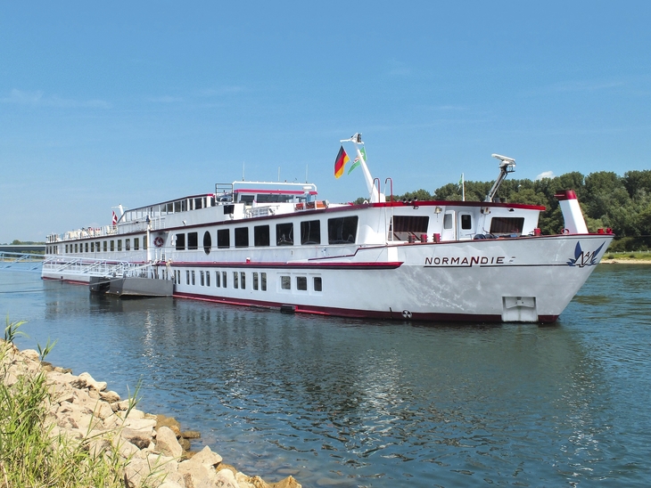 Kreuzfahrtschiff auf einem Fluss bei klarem Himmel und bewaldetem Ufer.