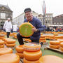 Verkäufer präsentiert Käselaib auf dem Käsemarkt von Gouda.