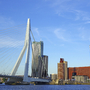Erasmusbrücke in Rotterdam vor moderner Skyline bei klarem Himmel.