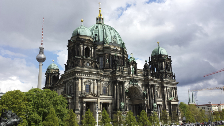 Berliner Dom mit Fernsehturm im Hintergrund bei bewölktem Himmel
