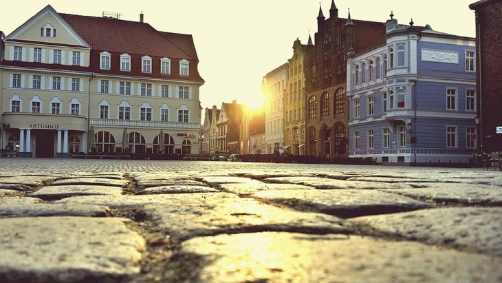 Altstadtplatz in Stralsund bei Sonnenuntergang, historische Gebäude im Hintergrund.