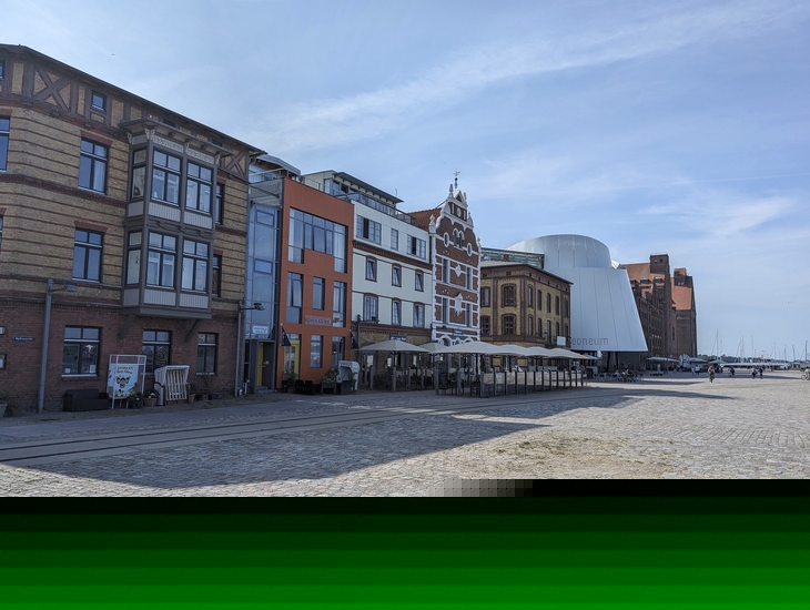 Gebäude am Hafen von Stralsund mit Ozeaneum im Hintergrund.