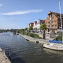 Hafenpromenade von Wolgast mit Segelboot und historischen Gebäuden bei Sonnenschein.