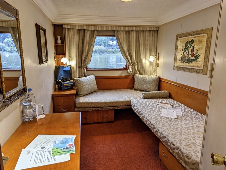 Kajüte mit Bett, Fenster, Tisch und Dekoration auf einem Schiff.