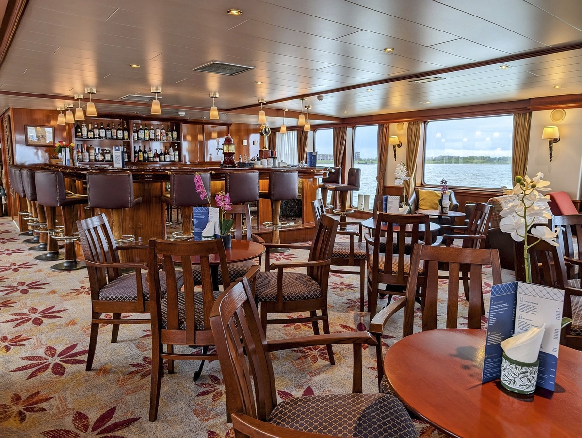 Innenraum einer stilvollen Schiffsbar mit Tischen und Barhockern.