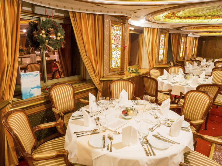 Elegantes Schiffrestaurant mit gedeckten Tischen und dekorativen Wandverkleidungen.