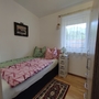 Kleines Schlafzimmer mit Einzelbett, Fenster mit Vorhang, Wandbild und Teppich.