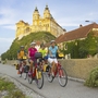 Radfahrer vor dem Stift Melk auf dem Donau-Radweg im Sonnenuntergang.